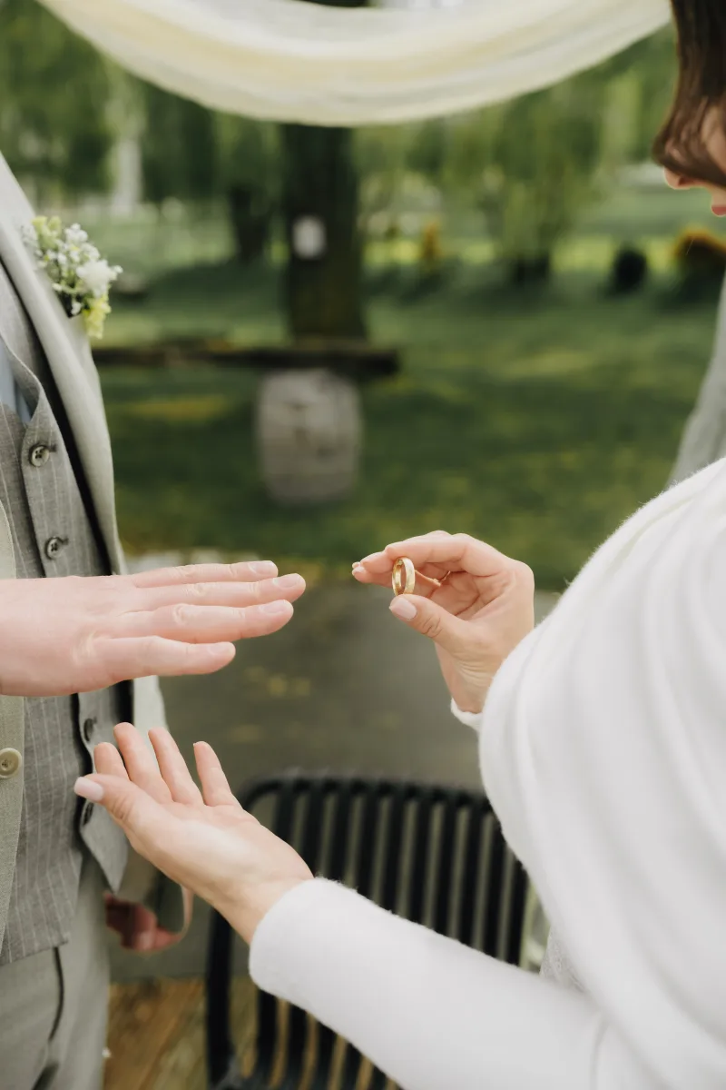 Eine Frau steckt ihrem Partner bei der Zeremonie den Ring an den Finger