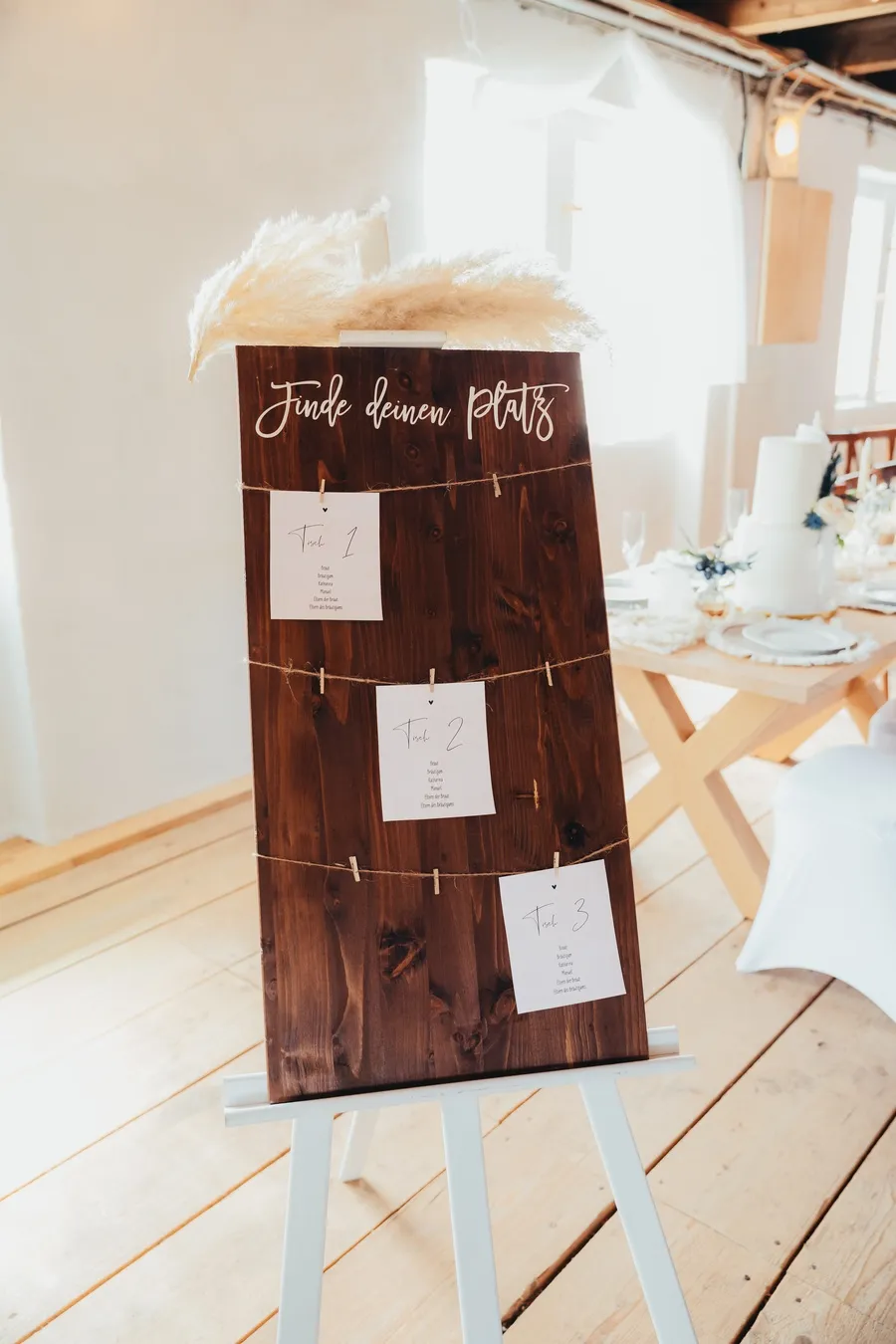 Holztafel „Finde deinen Platz“ mit Sitzplan-Kärtchen auf einer Staffelei