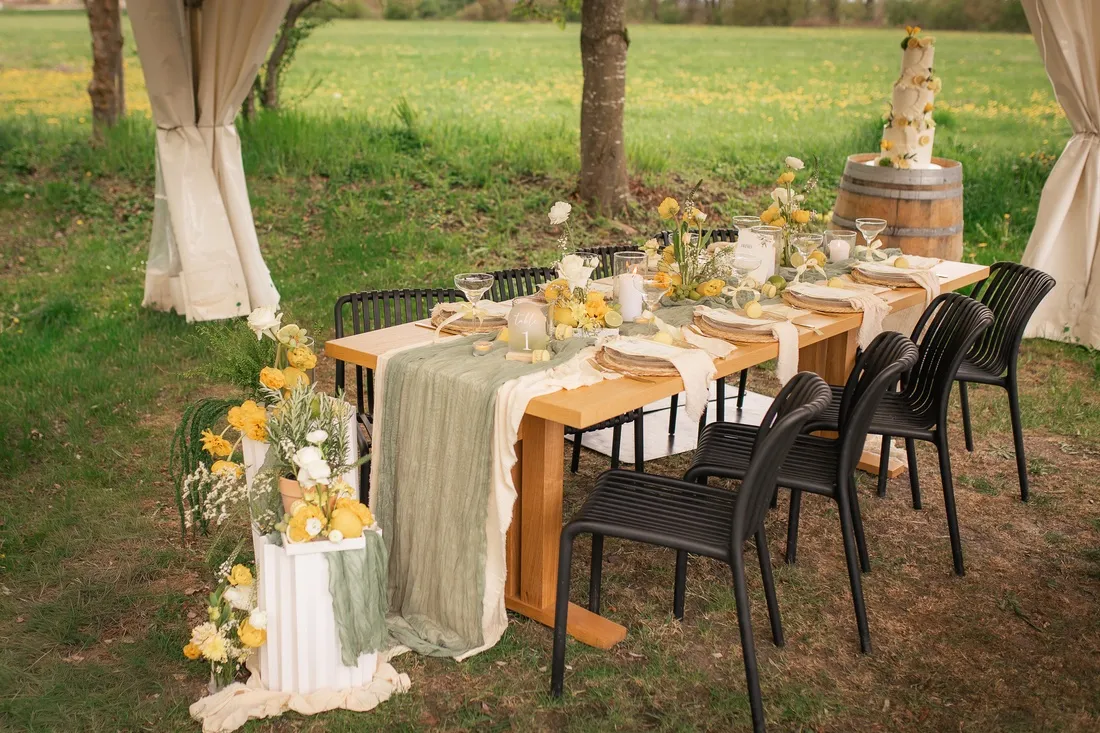 Lange gedeckte Tafel im Grünen mit gelben Blumen beim Styled Shooting in Ipsheim