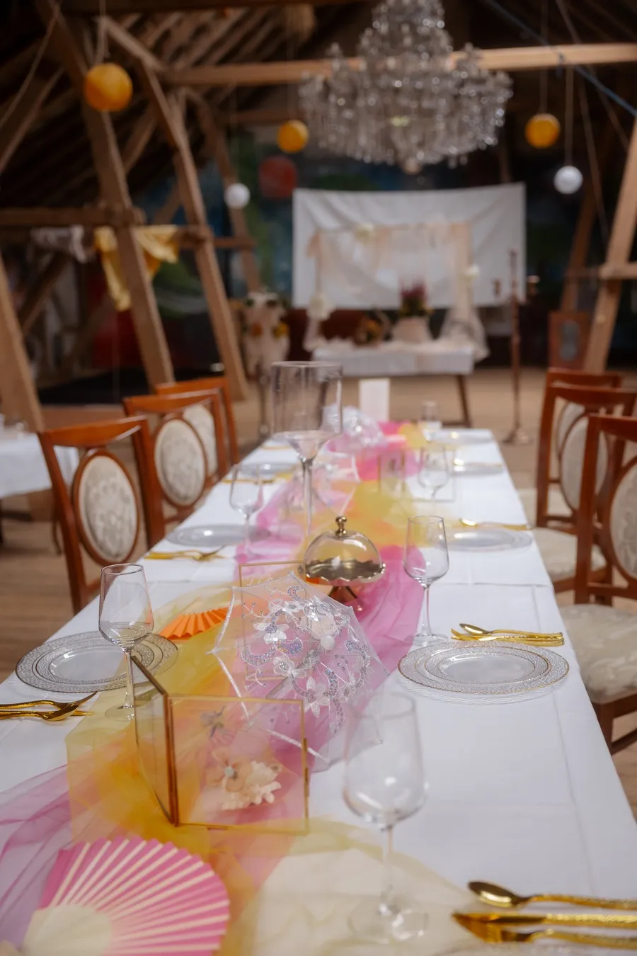 Lange weiße Tafel mit pinkem Tüll in der Scheune von Schloss Weitersroda