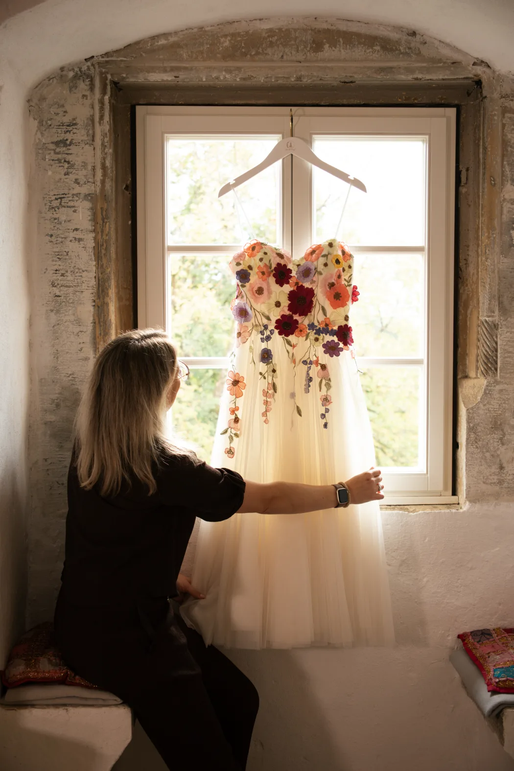 Yvonne Krienke richtet das Brautkleid am Fenster auf Schloss Weitersroda